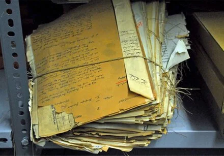 Zusammenarbeit im Archiv: Regale mit Akten und Fotos